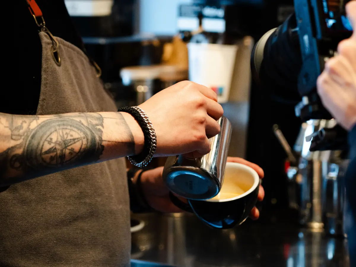 Barista häller latte art vid en Eversys i ett kafé