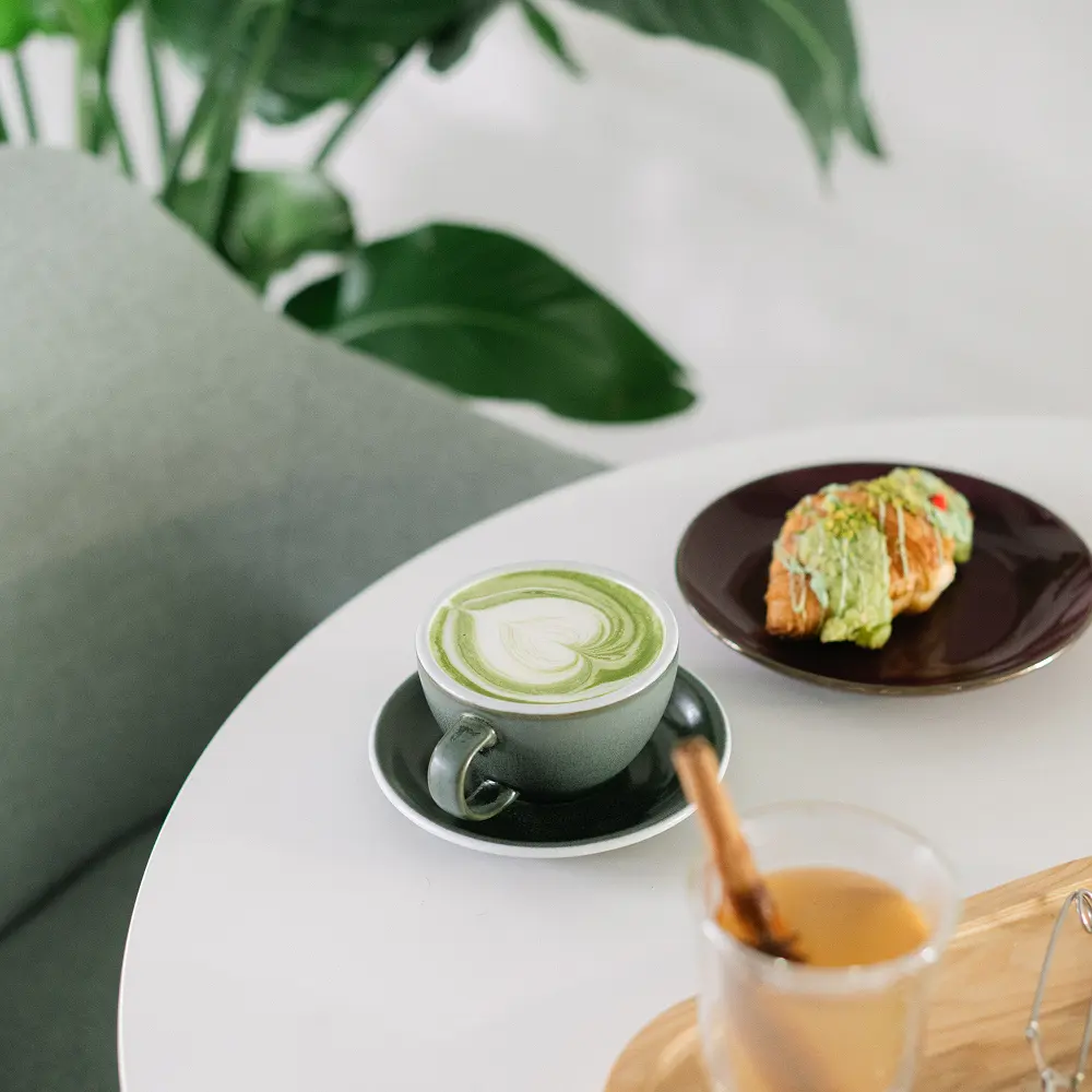 Matcha latte och bakverk på ett vitt bord