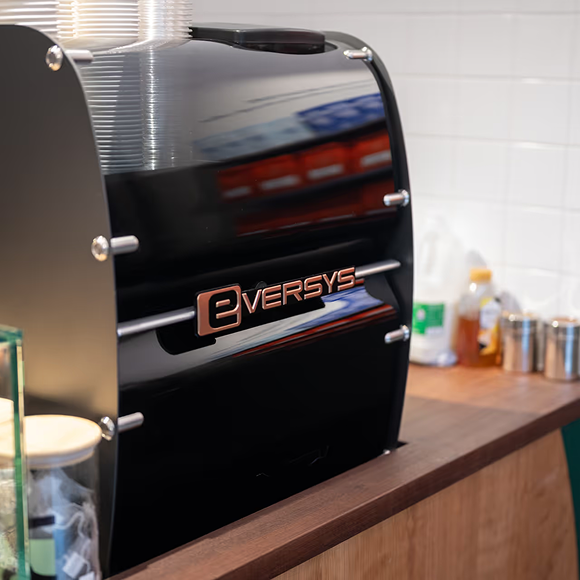 Eversys espressomaskin framför hyllor i en butik