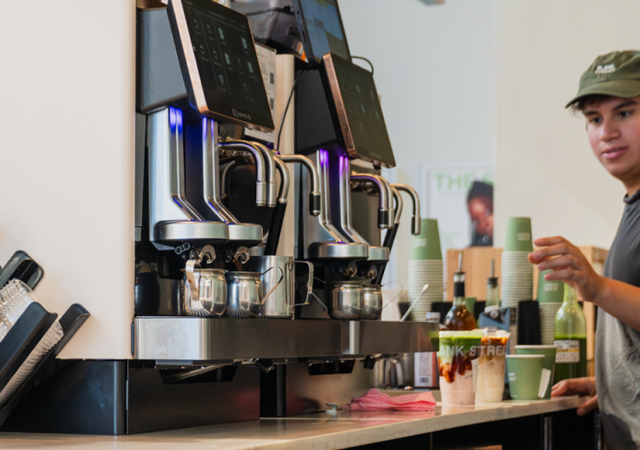 Barista bakom baren i ett café med flera Eversys kaffemaskiner