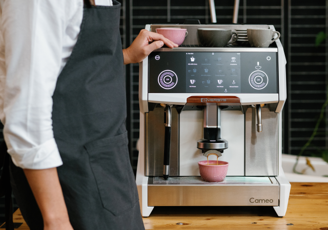 Barista i förkläde vid en Eversys Cameo espressomaskin